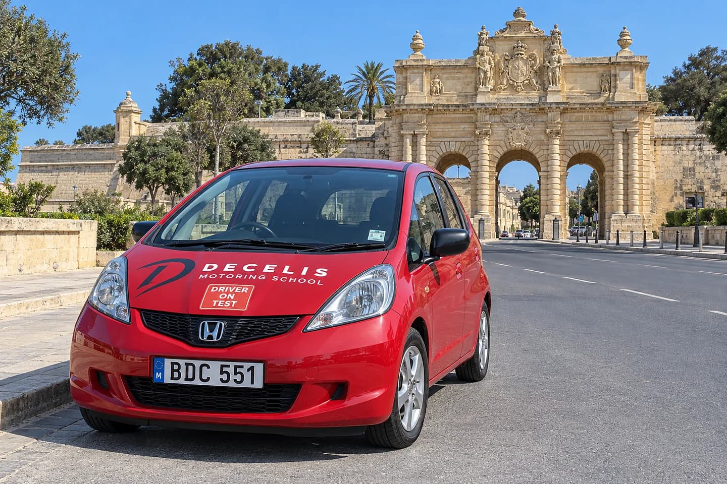 A red Decelis Honda Jazz with a Driver on Test sticker by the Porte des Bombes in Floriana