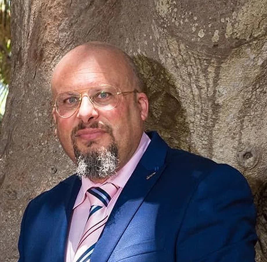 Darren Decelis in a navy suit and glasses